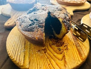 A round cake with a dusting of powdered sugar on a wooden board. - Agriturismo La Sfruscià (San Gregorio Magno)