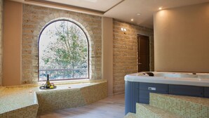 Un cuarto de spa con un amplio ventanal de arco, un jacuzzi y una zona de estar con suelo de baldosas.