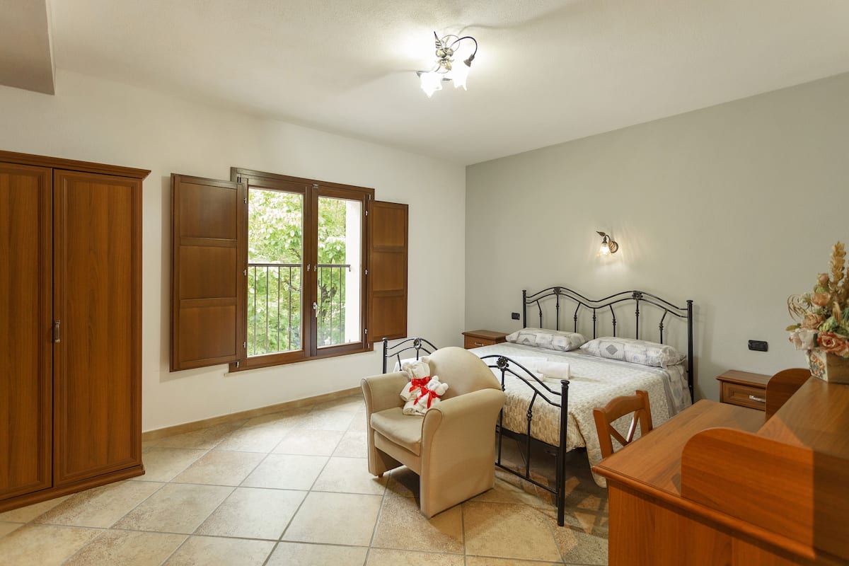Un dormitorio con cama, una silla, un escritorio y un armario.