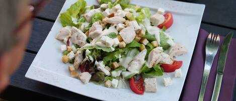 A white plate with a salad on a dark wooden table.
