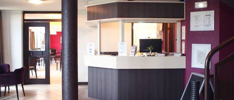 A reception area with a desk, chairs, a computer, and informational posters on the wall.