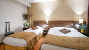 A hotel room with two beds, a wooden headboard, a small table, a nightstand, a lamp, a potted plant, and a suitcase. - Hôtel Inn Design & Restaurant Le Mans (Arnage)