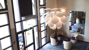 Ein modernes Interieur mit großen Fenstern, einer einzigartigen, kugelförmigen Leuchte und einer Sitzecke mit weißen und violetten Stühlen.