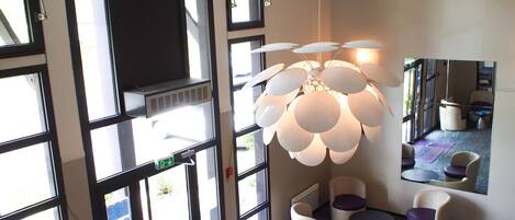 A modern interior with large windows, a unique spherical light fixture, and a seating area with white and purple chairs.