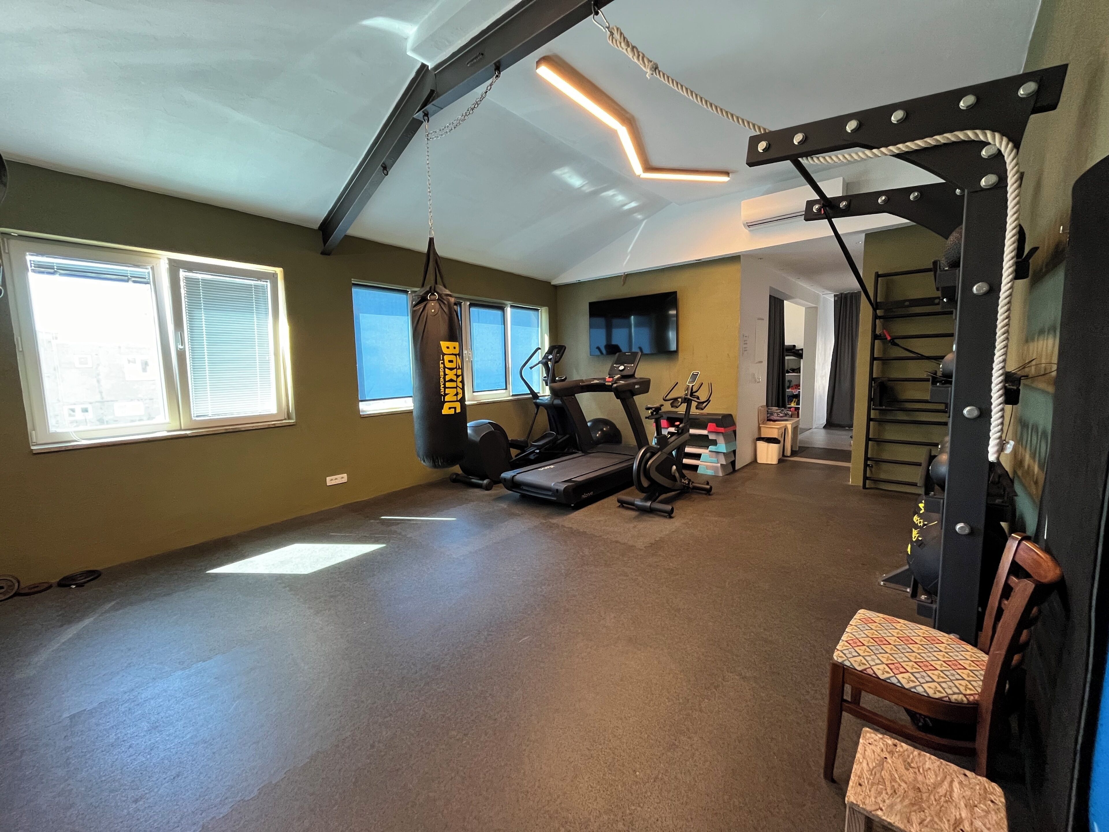A home gym with exercise equipment, a punching bag, and a staircase.