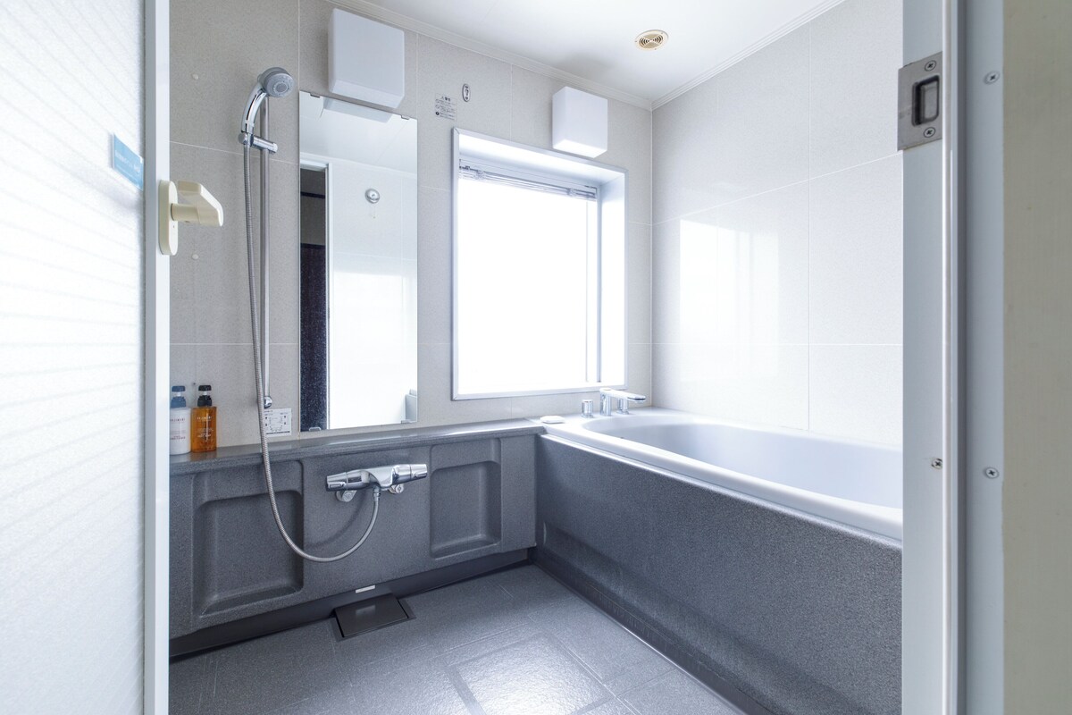 Un baño moderno con bañera, ducha y un espejo grande.
