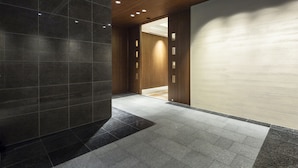 A modern hallway with dark tiled walls, a wooden ceiling, and recessed lighting. - Holiday Inn ANA Kanazawa Sky by IHG (Kanazawa)