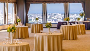 A banquet hall with round tables, each with a vase of flowers and wine glasses. - Holiday Inn ANA Kanazawa Sky by IHG (Kanazawa)