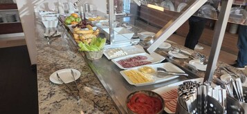 A buffet setup with various food items and utensils.