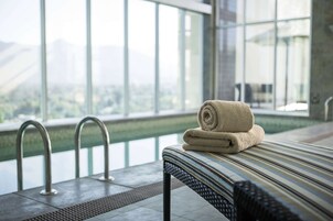 A modern indoor pool area with a view of a cityscape through large windows.