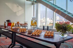 Um buffet de café da manhã com diversos alimentos e um vaso de flores.