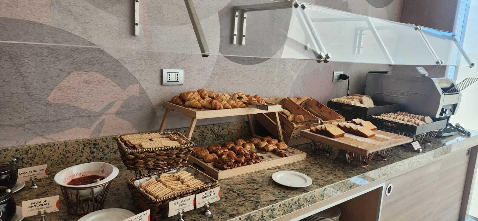 A breakfast buffet with various pastries, bread, and sauces.