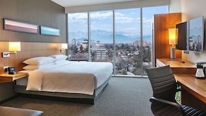 Habitación de hotel con una cama grande, un escritorio con silla, cafetera y televisor.