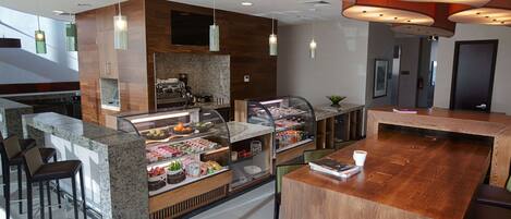 A modern café with a granite counter, bar stools, and a display case with pastries.