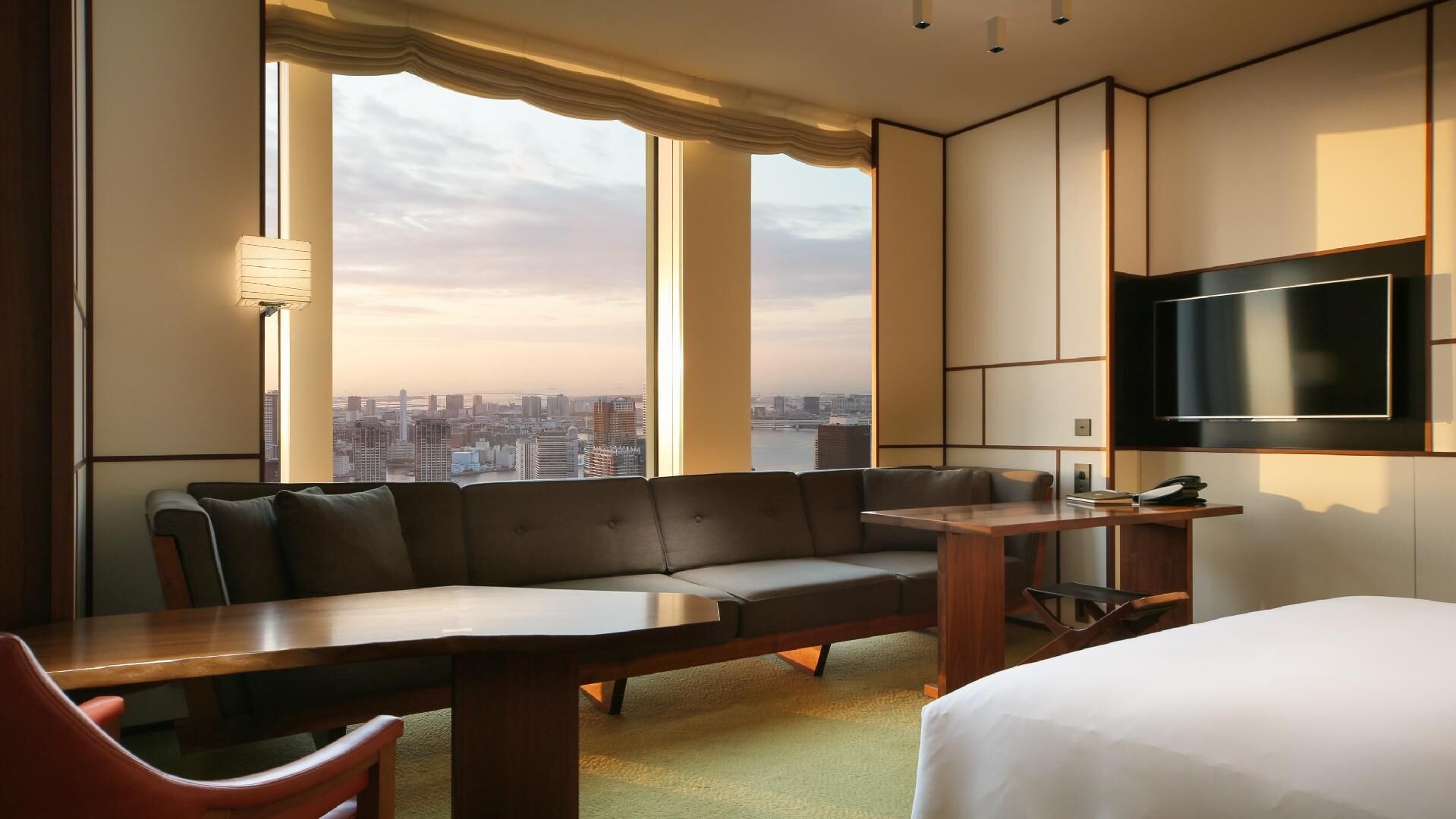 Una habitación de hotel con sofá, una mesita, cama y televisión.