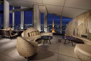 A modern lounge with a panoramic city view, featuring a sofa, chairs, and a round table. - Andaz Tokyo Toranomon Hills - a concept by Hyatt (Tokyo)