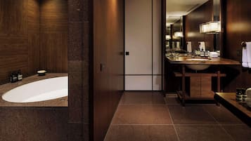 A modern bathroom with a freestanding bathtub, a vanity with a mirror, and a large mirror above the sink.