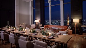 Een eetgedeelte met een lange tafel gedekt voor een maaltijd, omringd door stoelen, met een stadsgezicht waarop de Eiffeltoren zichtbaar is.