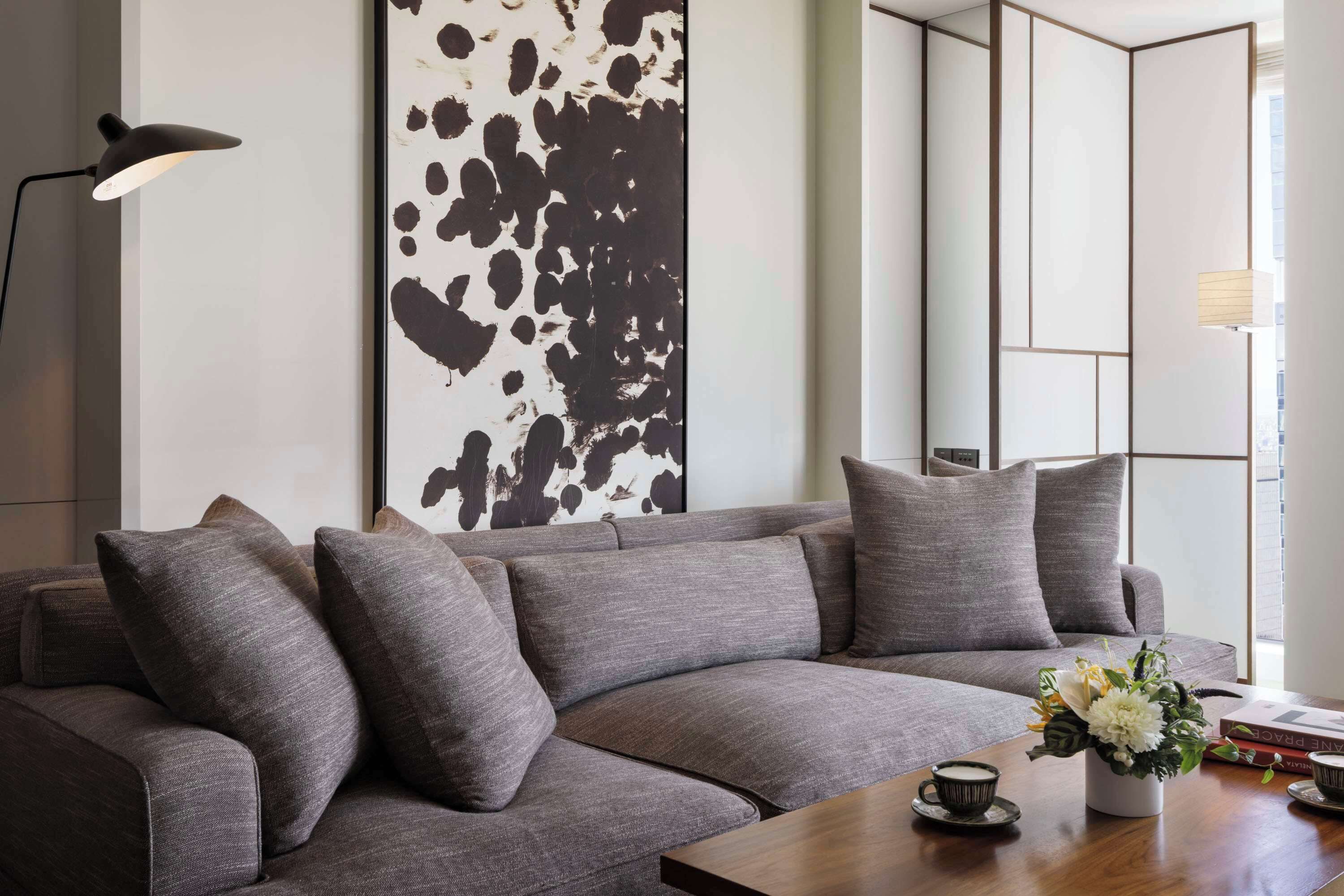A modern living room with a gray sofa, a coffee table, and a decorative vase with flowers.