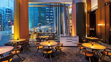 A modern indoor dining area with hexagonal patterned flooring, round tables, and wooden chairs.