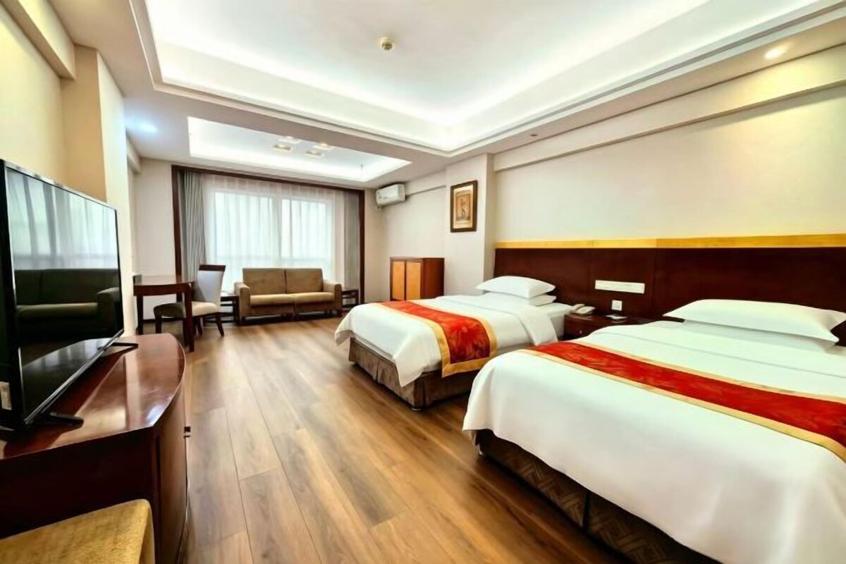 A hotel room with two beds, a TV, a desk, and a chair.