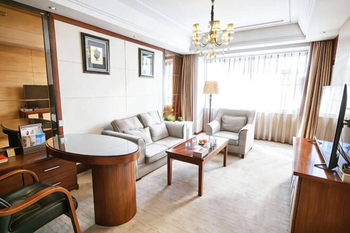 Ett hotellrum med en soffa, ett soffbord, en tv, ett skrivbord och en stol.