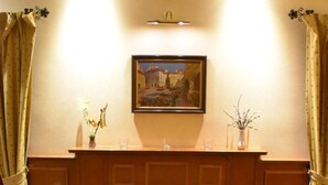 A cozy room with a fireplace, a painting above it, and two chairs around a small table. - Hotel Arbes (Prague)