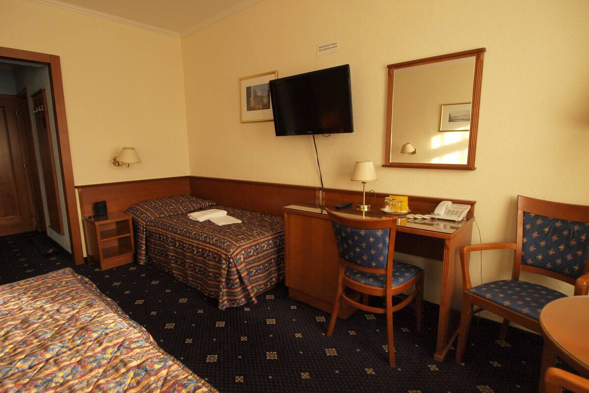 A hotel room with a bed, desk, chair, and a television.