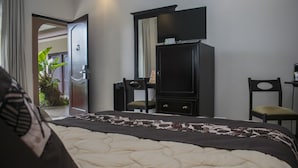 Habitación de hotel con cama, escritorio, silla, televisor y armario.