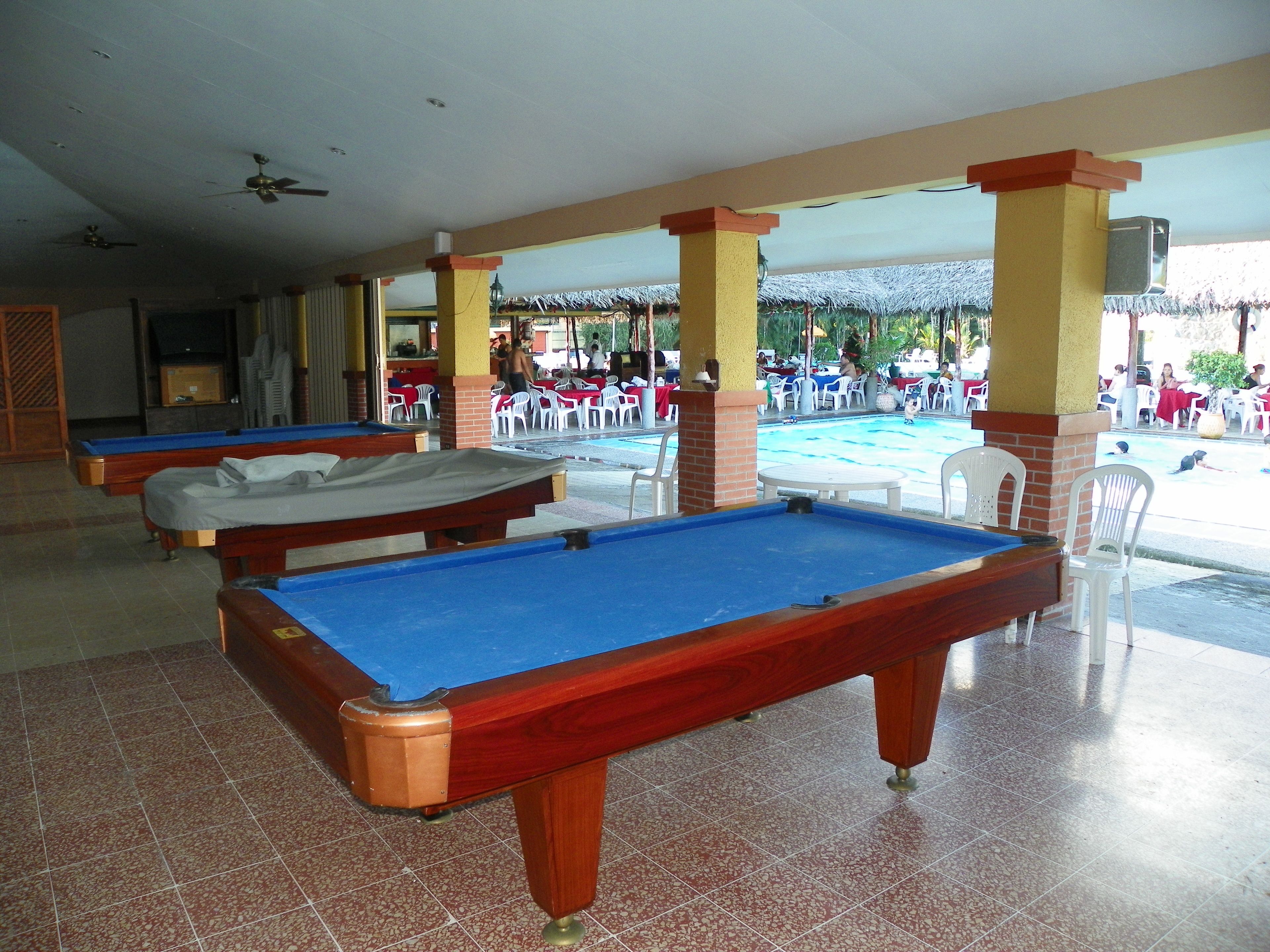 A pool area with multiple pool tables and outdoor seating.