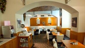 A restaurant with a brick archway, wooden cabinets, and a patterned carpet. - Hotel Máchova (Prague)