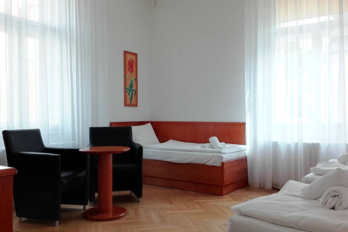 A hotel room with a bed, a desk, two chairs, and a small table.