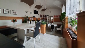 A modern dining area with a high ceiling, pendant lighting, and a mix of seating arrangements. - Pension Jana - Domov Mládeže (Prague)
