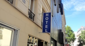 A hotel sign on a building with a balcony and a window. - Hotel Santana (Paris)
