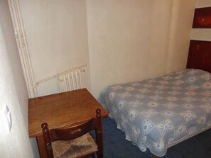 A small room with a wooden table and a patterned bed.