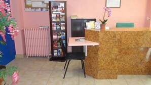 A reception desk with a computer, a bulletin board, a clock, and a plant. - Hotel Santana (Paris)