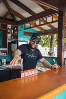 Een barman achter een bar met houten balken, die drankjes bereidt.