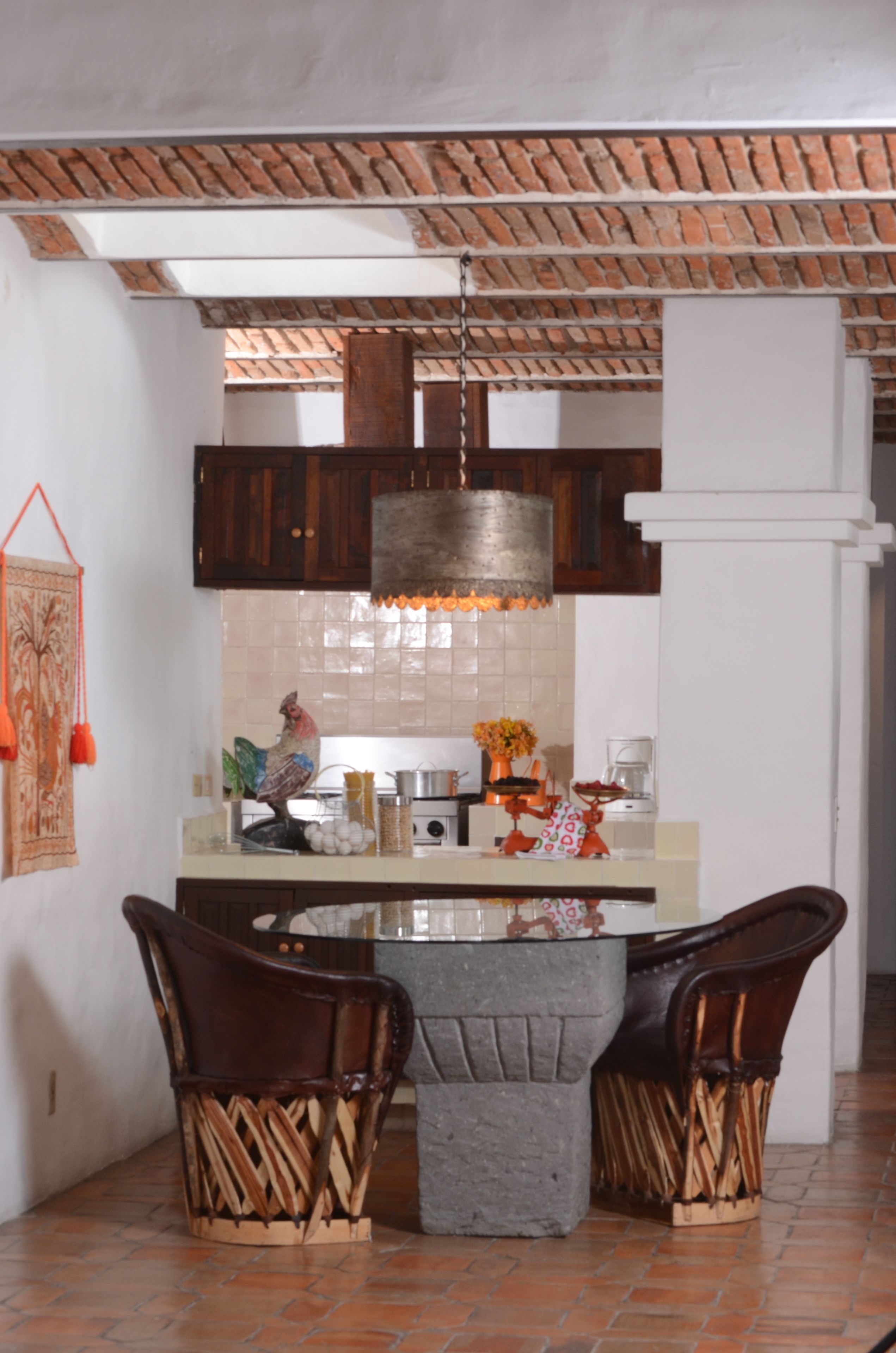 Una cocina con techo de ladrillo, armarios de madera, una isla central con sillas y una lámpara colgante.