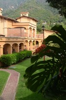 Un edificio con un patio, sendero de ladrillos y abundante vegetación.