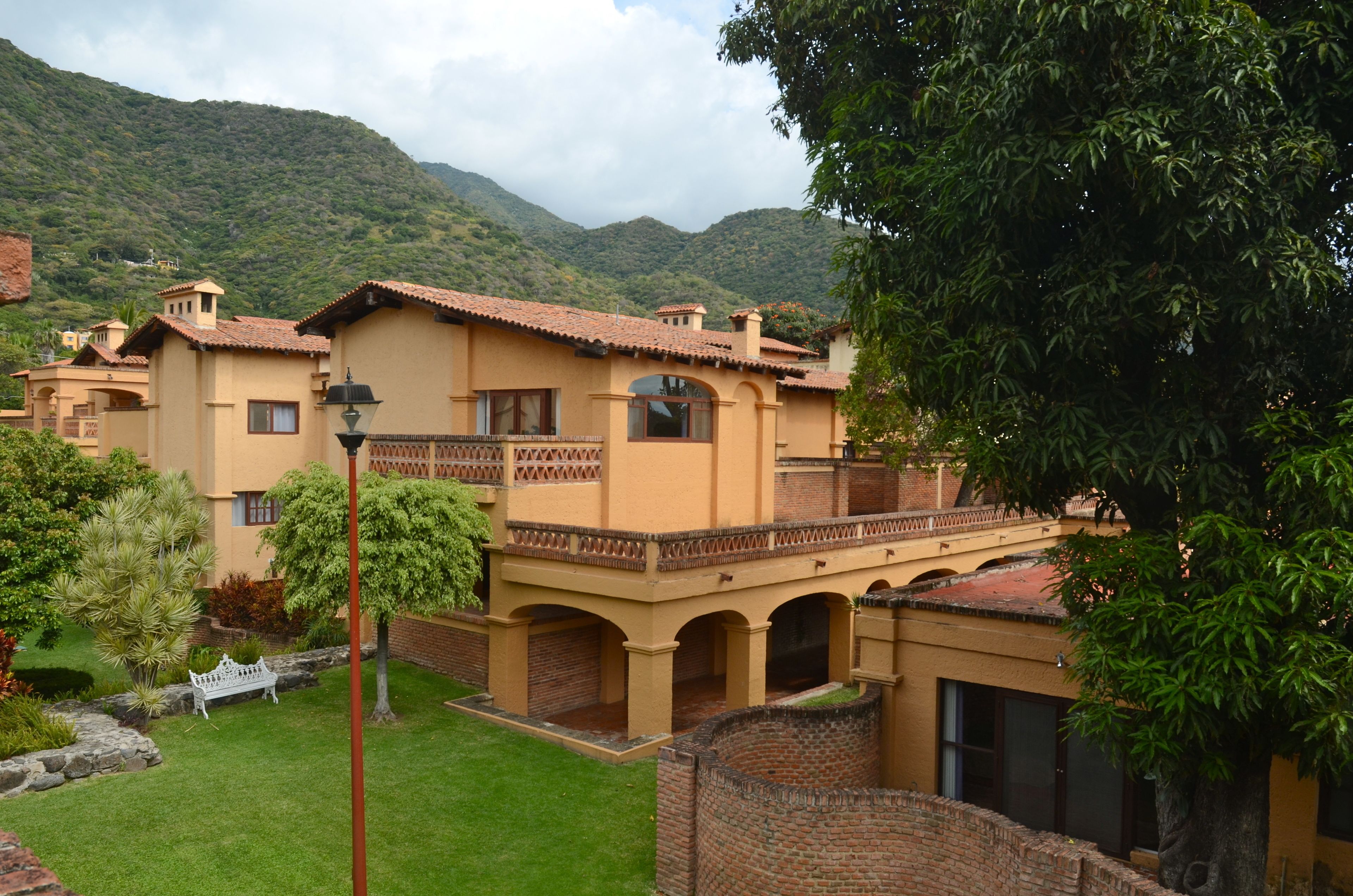 A traditional building with a courtyard, surrounded by lush greenery and hills.