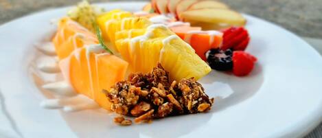 Une assiette remplie d’un assortiment de fruits et de granola, posée sur une table.