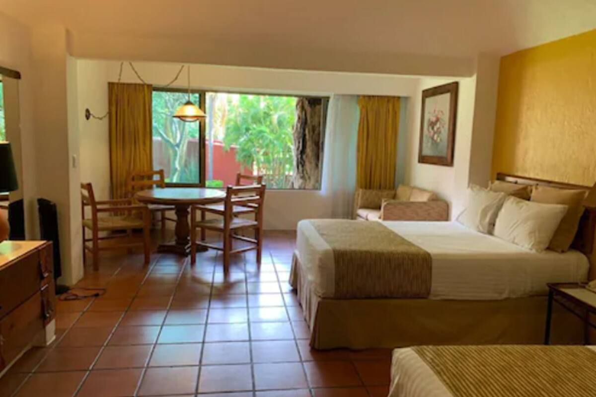 A hotel room with a bed, a desk, and a dining table.