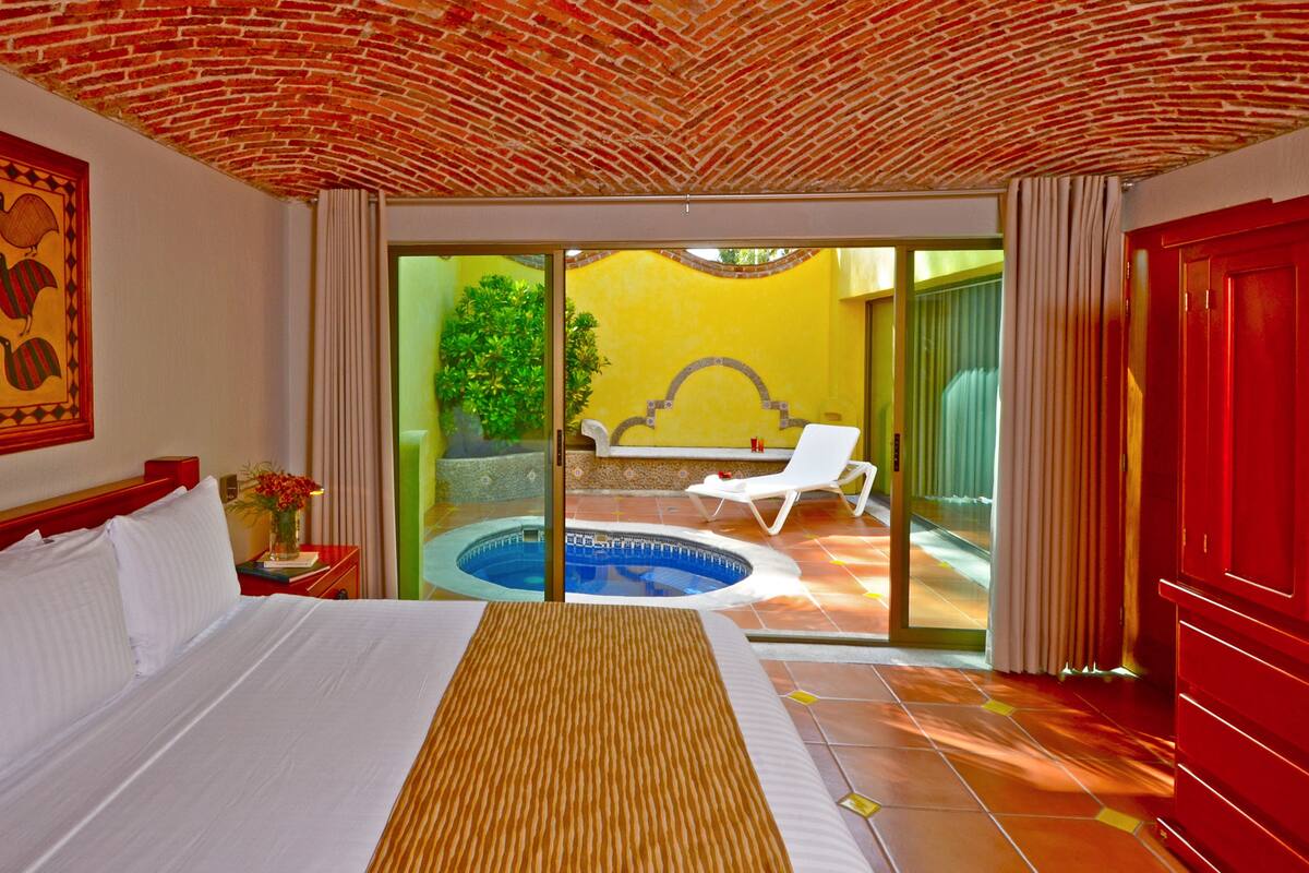 A hotel room with a bed, a small pool, and a view of the outside.