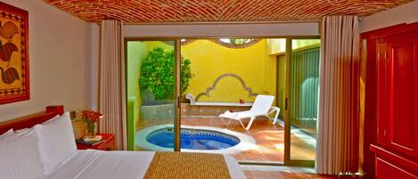 Habitación de hotel con cama, una piscina pequeña y vistas al exterior.