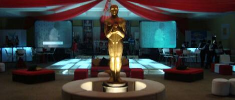 A lobby with a central golden statue, red drapes, and multiple screens displaying content.