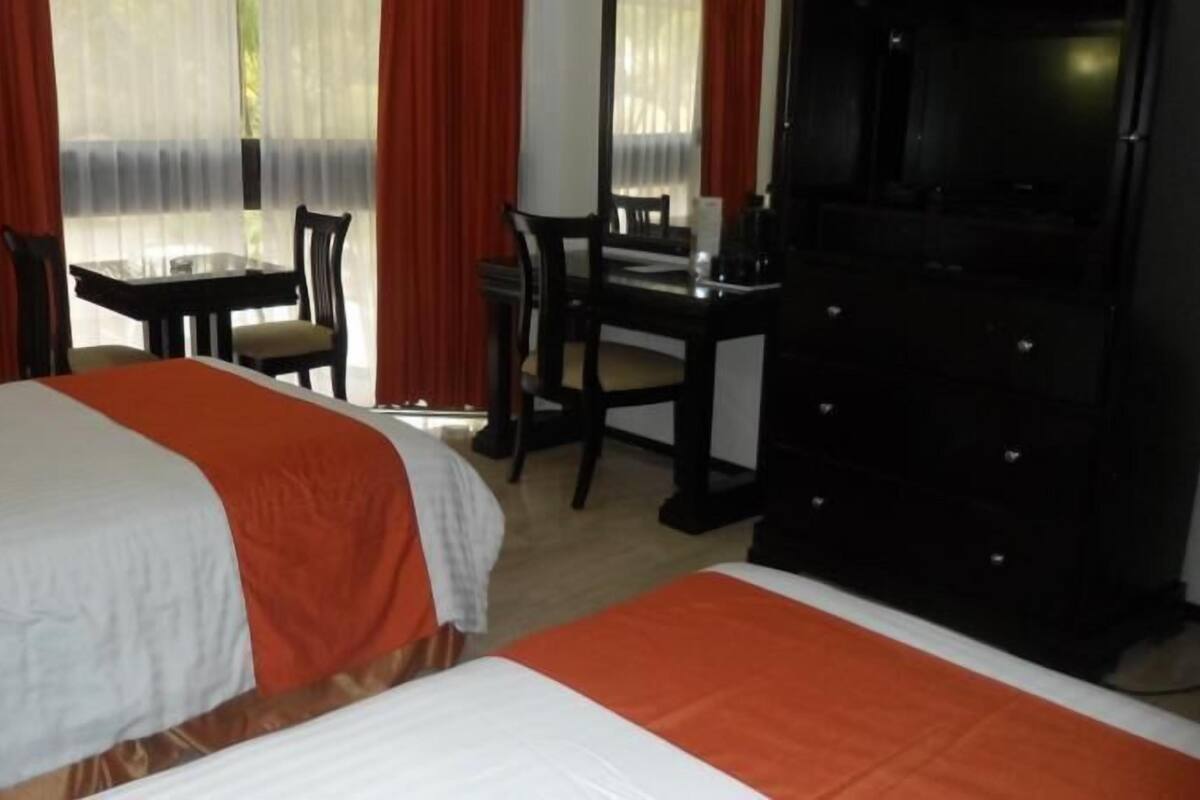 Ett hotellrum med två sängar, ett skrivbord och en TV.
