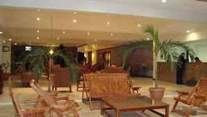 A lobby with wicker furniture, potted plants, and a reception desk. - Hotel Poza Rica Inn (Poza Rica)