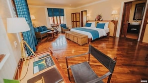 A spacious hotel room with a large bed, a desk with a chair, a small seating area with a table and chairs, and a ceiling fan. - Bagan Lodge (Nyaung-U)