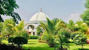 A garden with a white dome structure, surrounded by lush greenery and palm trees. - Bagan Lodge (Nyaung-U)