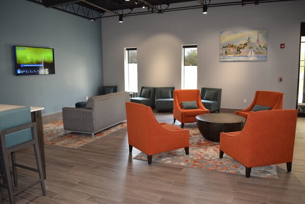A modern lounge area with seating, a flat-screen TV, and artwork on the wall.